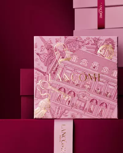 Elegantni kompozice růžovych a vinově červenych darkovych krabiček Lancome s centralni krabičkou zdobenou zlatymi ilustracemi pařižske architektury.