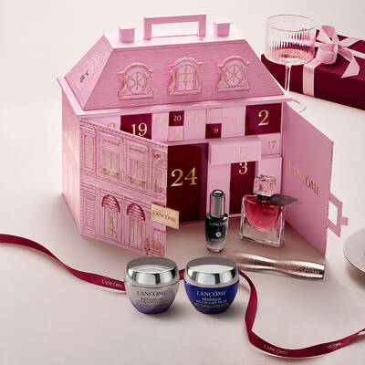 Otevřeny růžovy adventni kalendař Lancome ve tvaru pařižskeho palace s vystavenymi kosmetickymi produkty a červenou stuhou.