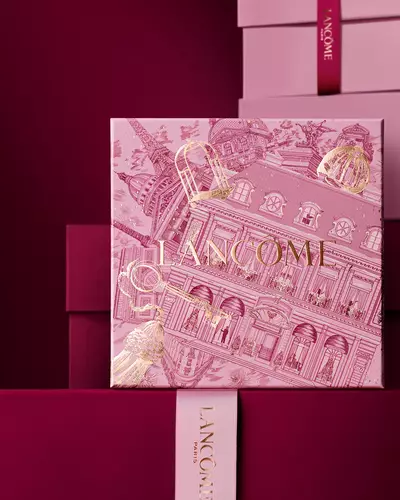 Elegantni kompozice růžovych a sytě vinovych darkovych krabiček Lancome, jejimž středobodem je krabička zdobena zlatymi ilustracemi pařižske architektury.