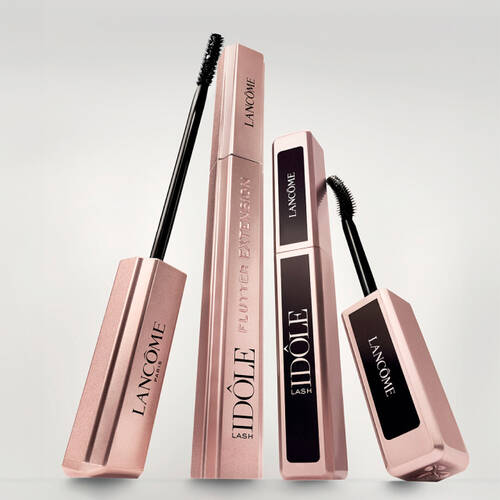 Tři řasenky značky Lancome v elegantnich obalech na světlem pozadi.