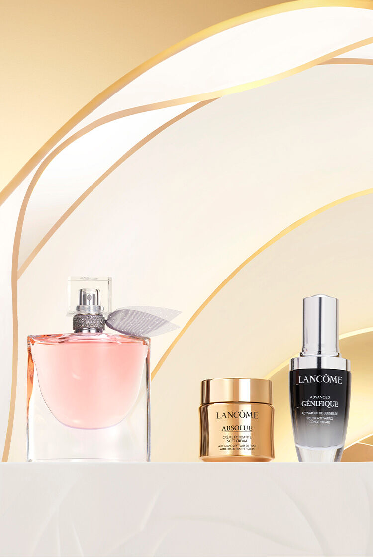 Na obrazku jsou kosmeticke produkty značky Lancome, včetně parfemu a pleťovych ser, umistěne na elegantnim pozadi se zlatymi tony.