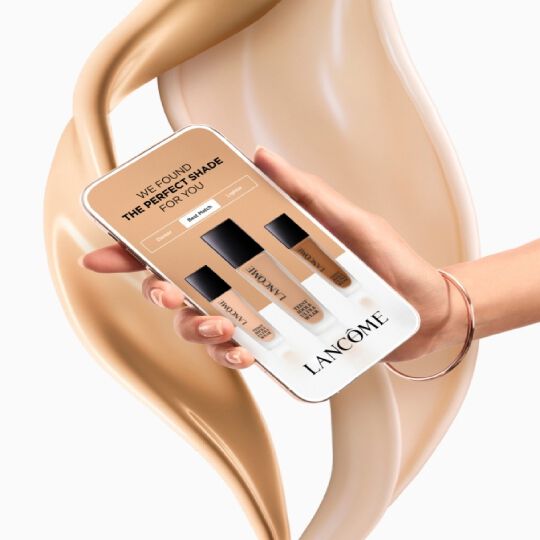 K telefonu se zobrazenim nazvu produktu Lancome a třemi odstiny make-upu na pozadi kremu.