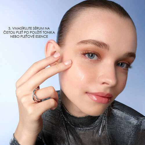 Modelka s čistou pleti ukazuje aplikaci sera na obličeji, moderni pozadi.