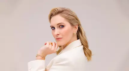 Žena v bilem saku se elegantně usmiva a drži si ruku u brady. Vedle ni je napis "Zorka Hejdova".