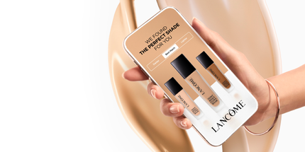 Ruka držici mobilni telefon s aplikaci, ktera doporučuje idealni odstin make-upu značky Lancome. Na obrazovce jsou zobrazeny tři odstiny make-upu.