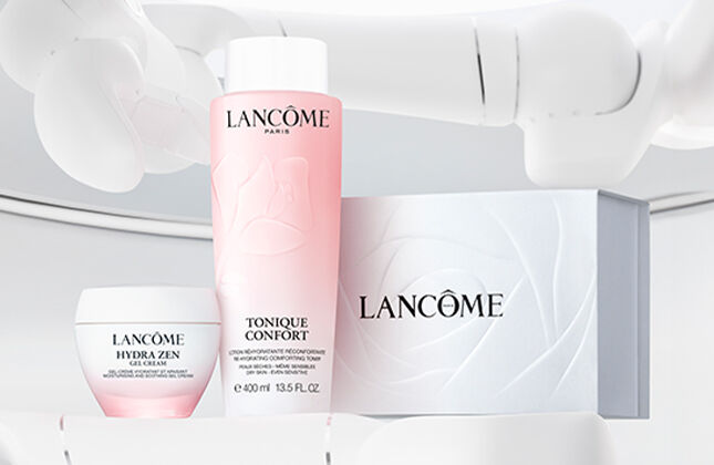 A display of Lancome skincare products, including a pink toner, a cream, and a box, set against a minimalist white background.