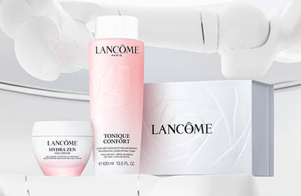 A display of Lancome skincare products, including a pink toner, a cream, and a box, set against a minimalist white background.
