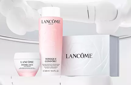 A clean, minimalist display featuring Lancome skincare products, including a pink toner, a cream, and a white box, set against a light background.