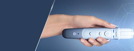 A hand holding a facial device aimed at a woman's face, with a high-tech digital interface displayed beside her.