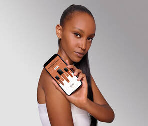 Žena držici mobilni telefon s aplikaci na vyběr odstinu pleti.