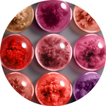 Barevne skleněne kuličky různych odstinů červene a fialove, uspořadane do vzoru na šedem pozadi.