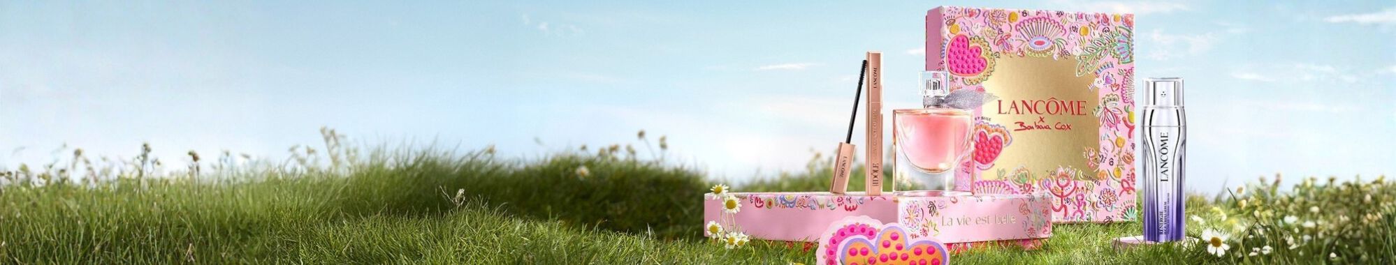 Vanočni darkove sady Lancome v růžovych krabicich ve vintage stylu na pozadi zasněženych hor.