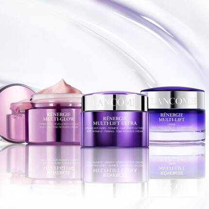 Tři kosmeticke produkty značky Lancome na bilem pozadi, včetně kremu a ser.