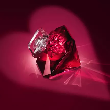 A decorative perfume bottle with a crystal lid and a flower design on a deep red background, creating a romantic and luxurious atmosphere.