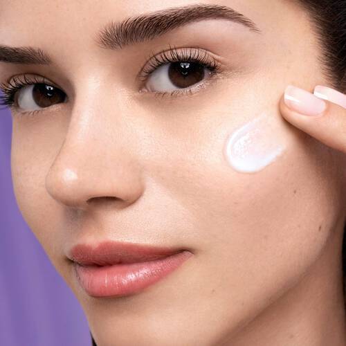 Žena nanaši pleťovy krem na tvař, ma hladkou pleť a vyzařuje zdravy vzhled.