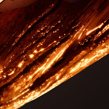 Detailni zaběr na barvene dřevo s prosvětlenymi prasklinami, ktere vytvařeji teplou atmosferu.