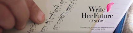 A close-up of a person's hand holding a notebook with Arabic text, accompanied by the Lancome logo and the phrase "Write Her Future."