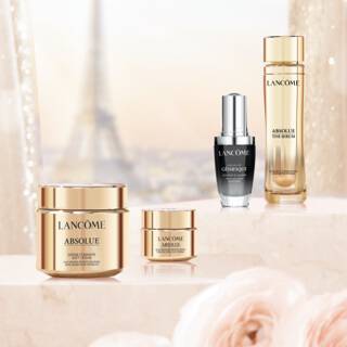 A display of luxurious skincare products by Lancome, including jars and bottles, set against a soft, sparkling background with a hint of the Eiffel Tower.