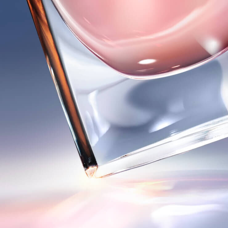 Sklenice s napojem, kterou drži ruka, s jemnymi odlesky na povrchu.